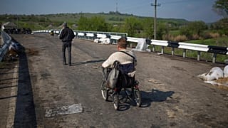 A disabled person goes over the bridge on a wheelchair at a pro-Russian insurgent checkpoint that has been used to block access to a road leading to Slovyansk, Ukraine. 