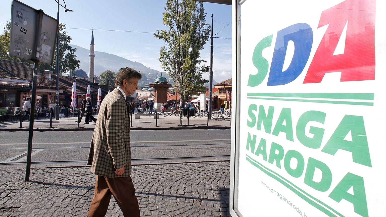 A Bosnian man passes by an election poster of the Party of Democratic Action (SDA) in Sarajevo, Bosnia, Saturday, Oct. 6, 2018.