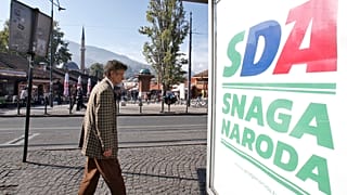 A Bosnian man passes by an election poster of the Party of Democratic Action (SDA) in Sarajevo, Bosnia, Saturday, Oct. 6, 2018.