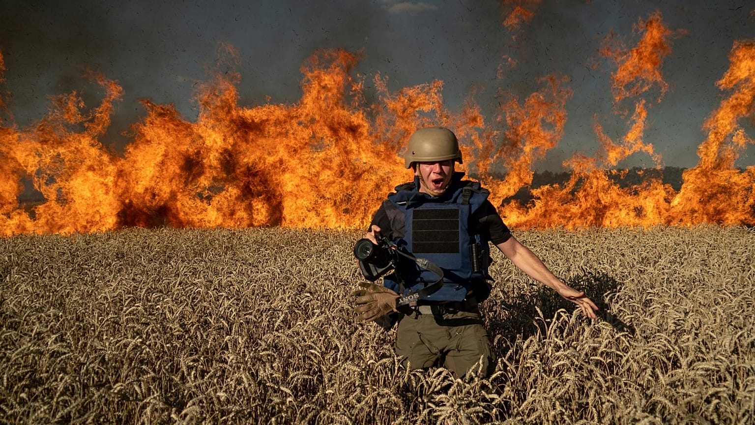 Photojournalist Evgeniy Maloletka runs from the fire in a burning wheat field during his assignment after Russian shelling, a few kilometres from Ukrainian-Russian border in t