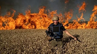 Photojournalist Evgeniy Maloletka runs from the fire in a burning wheat field during his assignment after Russian shelling, a few kilometres from Ukrainian-Russian border in t
