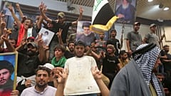 Iraqi protesters pose with national flags, a blood-stained shirt, and pictures of Shiite cleric Muqtada al-Sadr inside the Parliament building in Baghdad, 30 July 2022