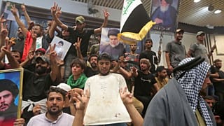 Iraqi protesters pose with national flags, a blood-stained shirt, and pictures of Shiite cleric Muqtada al-Sadr inside the Parliament building in Baghdad, 30 July 2022