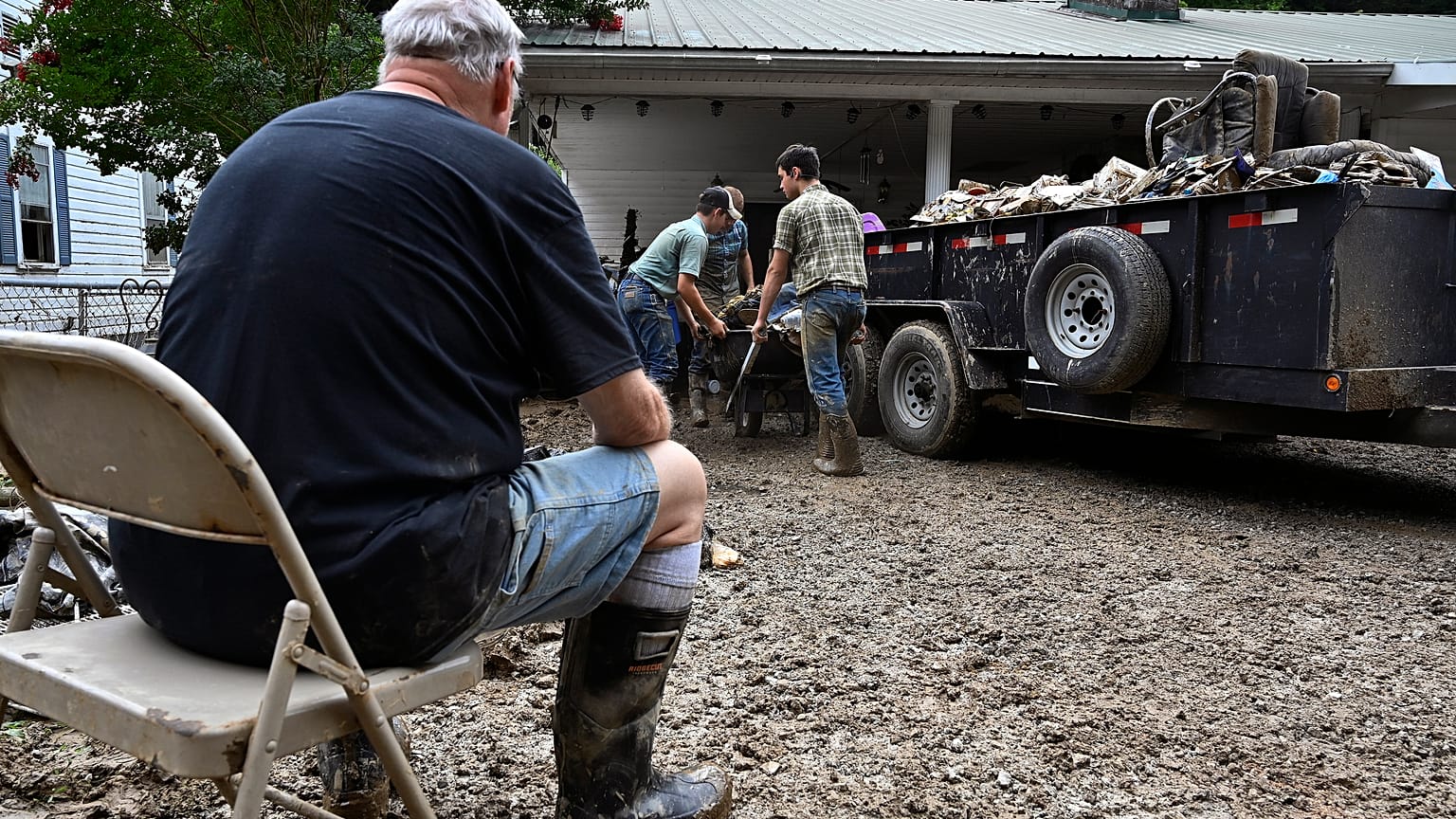 Un hombre se toma un descanso mientras los voluntarios limpian la propiedad dañada por las inundaciones de una casa Kentucky, el sábado 30 de julio de 2022.