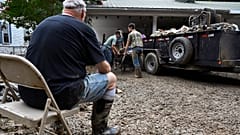 Un hombre se toma un descanso mientras los voluntarios limpian la propiedad dañada por las inundaciones de una casa Kentucky, el sábado 30 de julio de 2022.
