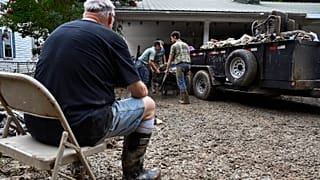 Un hombre se toma un descanso mientras los voluntarios limpian la propiedad dañada por las inundaciones de una casa Kentucky, el sábado 30 de julio de 2022.