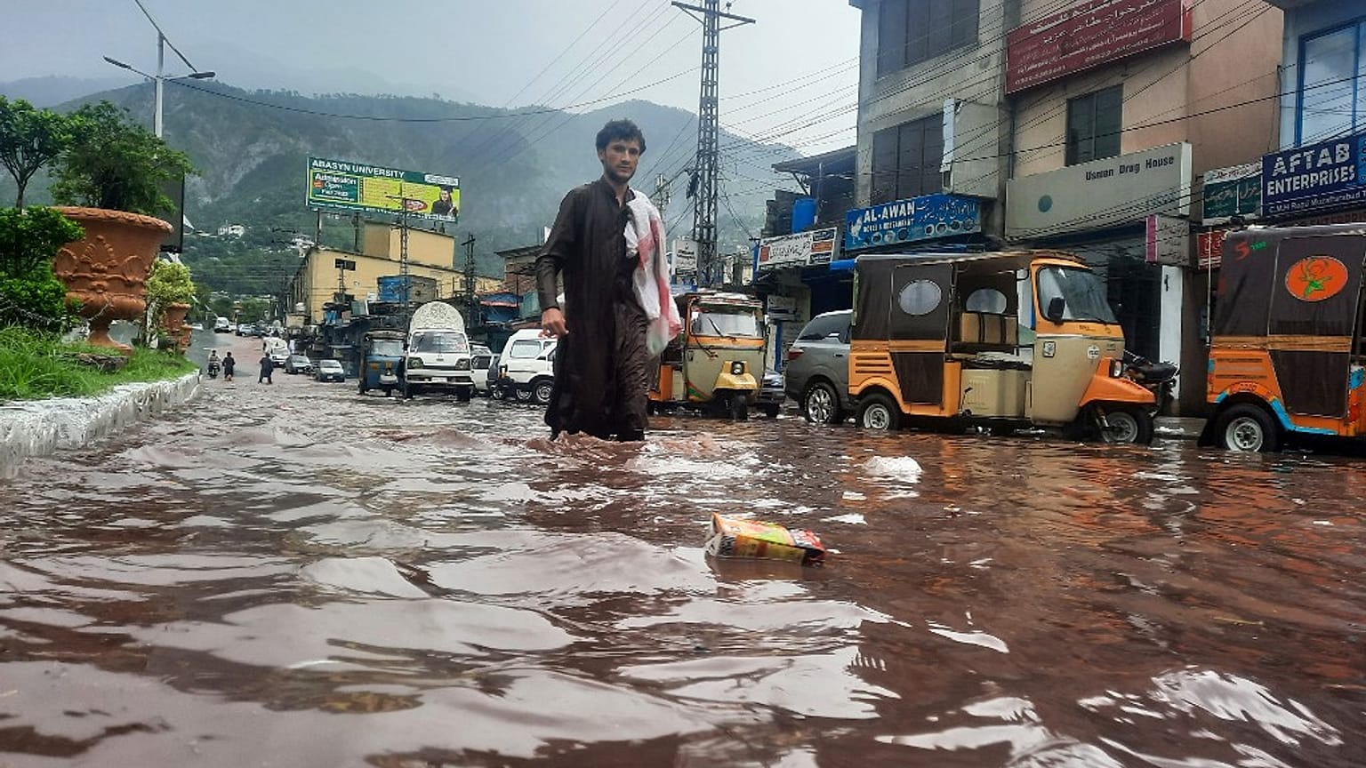Um homem atravessa uma rua inundada em Muzaffarabad, Paquistão