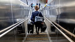 A woman carries her luggage down the stairs at the international airport in Frankfurt, 21 June 2022