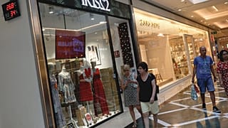 People walk by a thermometer displaying a temperature of 26.8 degrees Celsius at a shopping mall in Madrid, Spain.