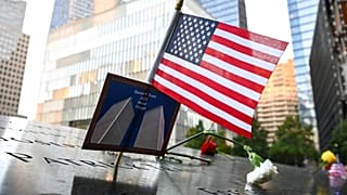 Bandeira dos EUA colocada juntamente com uma fotografia das Torres Gémeas em memorial das vítimas do 11 de setembro, Nova Iorque