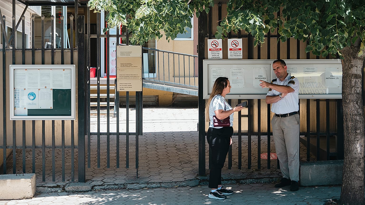 A security guard at the Swiss Embassy in Prishtina answers a question from a passerby, 14 July 2022