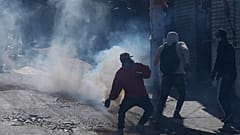 Un vendedor de coca devuelve un bote de gas lacrimógeno disparado por la policía antidisturbios durante el segundo día de protestas en La Paz