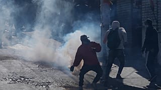 Un vendedor de coca devuelve un bote de gas lacrimógeno disparado por la policía antidisturbios durante el segundo día de protestas en La Paz