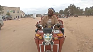 Danai Bvochora sur un tricycle électrique à Harare, au Zimbabwe