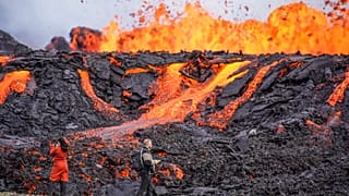 People look at the lava flowing on Fagradalsfjall volcano.
