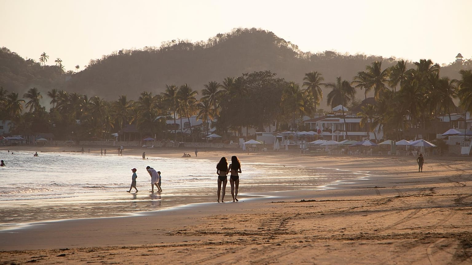 People walk on Manzanillo beach in Mexico. 