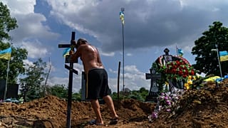 A cemetery worker places a cross on the grave of Serhiy Marchenko following his burial in Pokrovsk, Donetsk region, eastern Ukraine, Thursday, Aug. 4, 2022