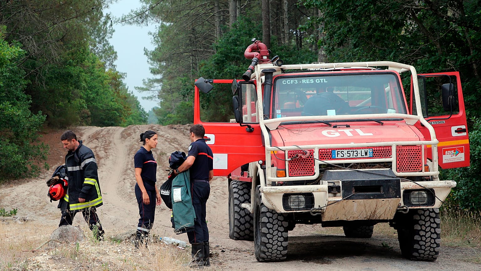 Des pompiers se tiennent à côté d'un camion de pompiers à La Teste-de-Buch, près d'Arcachon, dans le sud-ouest de la France, mardi 19 juillet 2022.
