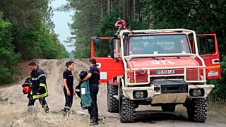 Firefighters stand next to a fire truck at La Test-de-Buch, near Arcachon, southwestern France, Tuesday, July 19, 2022