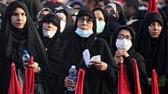 مشيعون يلوحون بالأعلام الحمراء وهم يتجمعون حول توابيت ملفوفة بالأعلام لخمسة من أعضاء الحرس الثوري شبه العسكري الذين قُتلوا في سوريا.