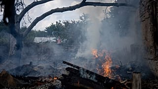 A local resident, back, tries to stop the fire at a neighbor's house destroyed by a Russian attack in Mykolaiv, Ukraine, Friday, Aug. 5, 2022.