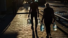 Egy házaspár vizes palackokat visz, miután feltöltötték őket egy boltban a kelet-ukrajnai Pokrovszkban, a donyecki régióban, 2022. augusztus 4-én. 