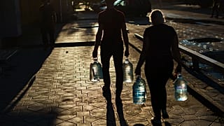 Egy házaspár vizes palackokat visz, miután feltöltötték őket egy boltban a kelet-ukrajnai Pokrovszkban, a donyecki régióban, 2022. augusztus 4-én. 