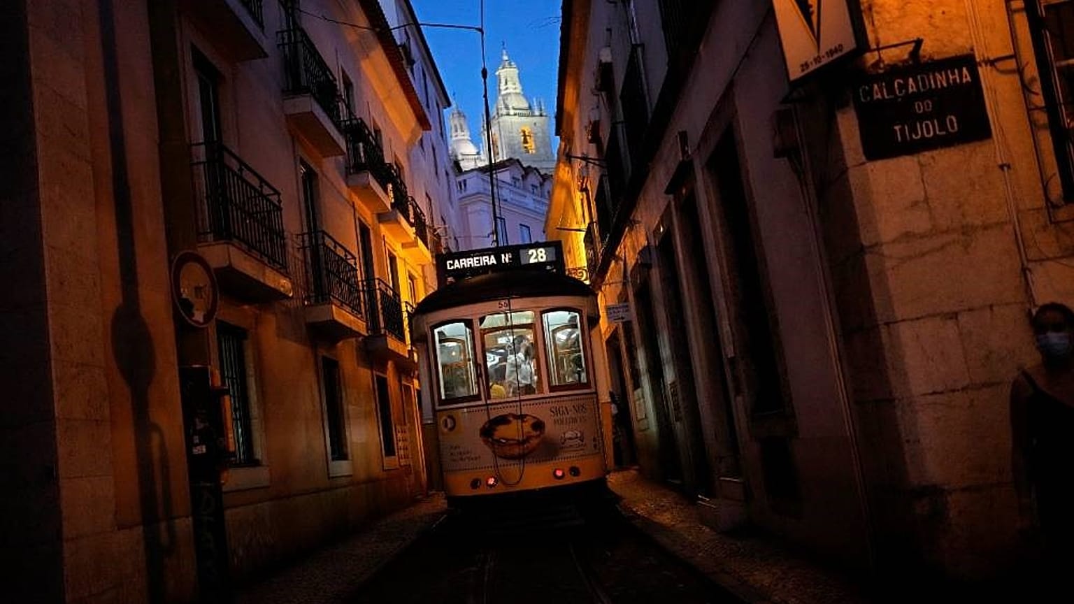 El tranvía número 28, uno de los favoritos de los turistas, circula por una estrecha calle del antiguo barrio lisboeta de Alfama al caer la noche.