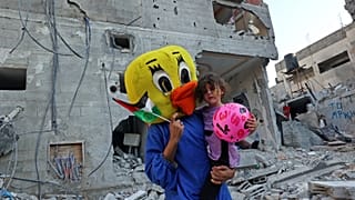 Clown vor Trümmern in Gaza.