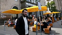 FILE - People, some of them still in masks to protect against coronavirus, enjoy outdoor McDonald's meal in downtown Kyiv, Ukraine, on June 9, 2020.