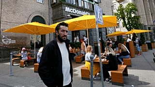 FILE - People, some of them still in masks to protect against coronavirus, enjoy outdoor McDonald's meal in downtown Kyiv, Ukraine, on June 9, 2020.