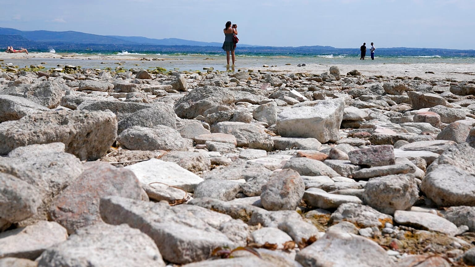 A woman takes pictures in the peninsula of Sirmione, on Garda lake, Italy, Friday, Aug. 12, 2022.