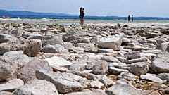 A woman takes pictures in the peninsula of Sirmione, on Garda lake, Italy, Friday, Aug. 12, 2022.