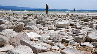 A woman takes pictures in the peninsula of Sirmione, on Garda lake, Italy, Friday, Aug. 12, 2022.