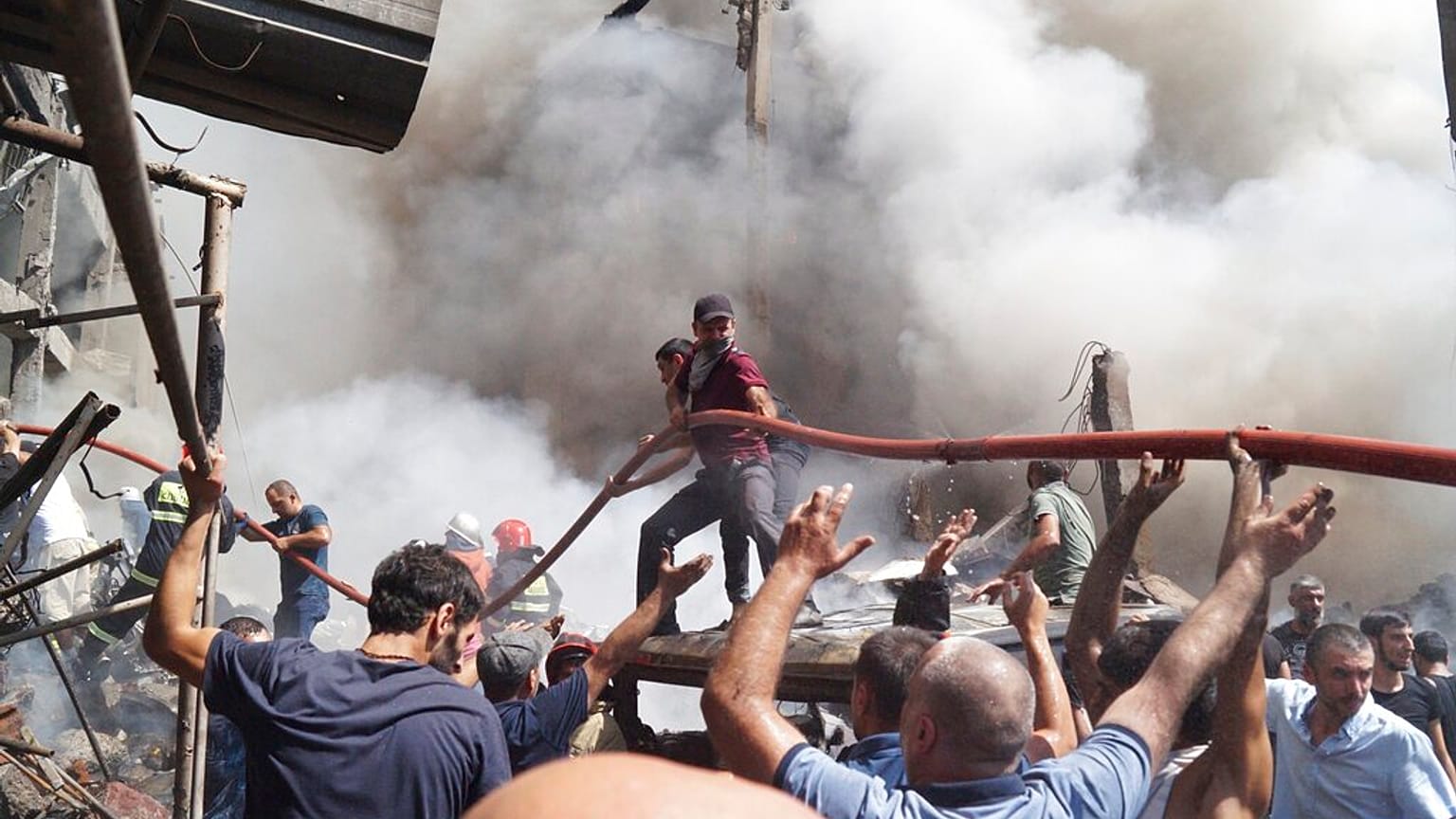 People help firefighters to deliver water to extinguish flames at Surmalu market about two kilometers (1.2 miles) south of the center Yerevan, Armenia, Sunday, Aug. 14, 2022.