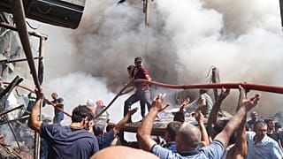 People help firefighters to deliver water to extinguish flames at Surmalu market about two kilometers (1.2 miles) south of the center Yerevan, Armenia, Sunday, Aug. 14, 2022.