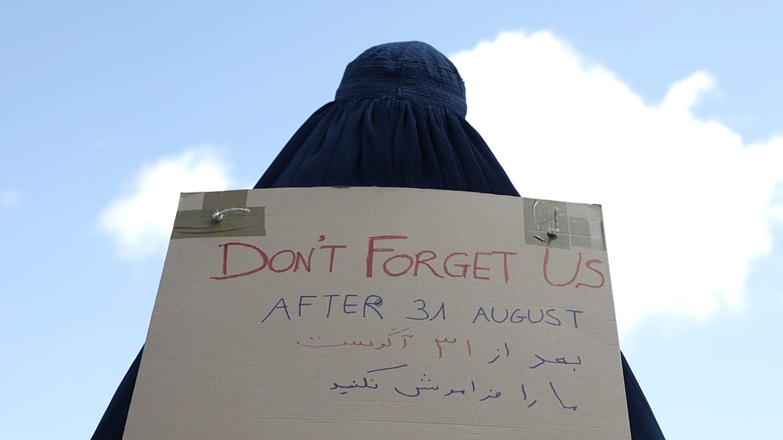سيدة أفغانية ترتدي البرقع وتحمل لافتة مكتوب عليها لا تنسونا أمام السفارة الفرنسية في كابول، أفغانستان.   