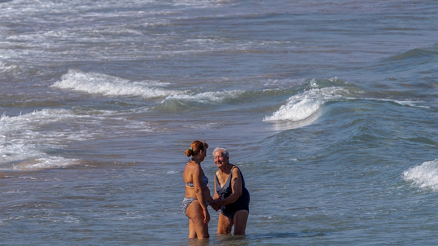 Zwei Frauen nehmen am Strand von Puerto de Sagunto ein Bad im Mittelmeer