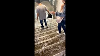 People walk as water rushes down the stairs following a heavy rainfall at Victor Hugo metro station in Paris, France August 16, 2022