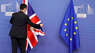 A member of protocol adjusts the EU and Union flag prior to an official greeting between the EU's Maros Sefcovic and the UK's Liz Truss, in Brussels, Feb. 21, 2022.