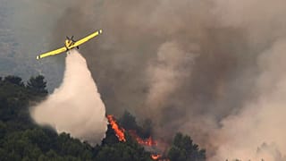 A firefighting plane drops water during fire extinguish works in Viver, eastern Spain, on Wednesday, Aug. 17, 2022.