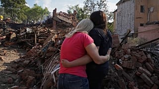 Украинки стоят перед разрушенным жилым домом в Харькове. 18 августа 2022.