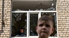 A worker cleans up inside as Tikhon Pavlov, 11, walks past the Kramatorsk College of Technologies and Design after a rocket attack in the city. 
