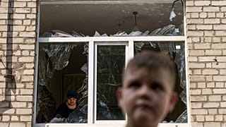 A worker cleans up inside as Tikhon Pavlov, 11, walks past the Kramatorsk College of Technologies and Design after a rocket attack in the city. 