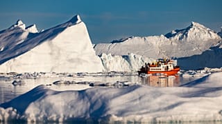 قارب يحمل السياح بين الجبال الجليدية العائمة في خليج ديسكو، إيلوليسات، غرب غرينلاند، 1 يوليو 2022
