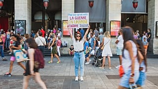 Diana Dimitrova, a Ukrainian from Kyiv holds a poster that reads in French 'For those who have forgotten: the war in Ukraine is still ongoing'. Lyon, France. August 2022
