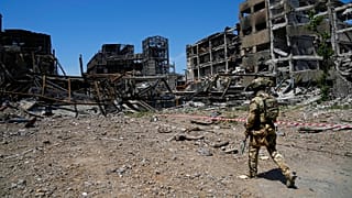A Russian soldier walks in front of the damaged Metallurgical Combine Azovstal plant, in Mariupol, 13 June 2022