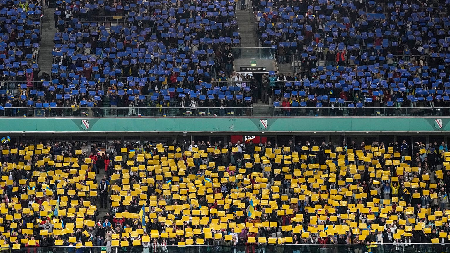 Spectators hold banners in colors of the Ukrainian flag before a friendly charity soccer match between Legia Warszawa and Dynamo Kyiv in Warsaw, 12 April 2022
