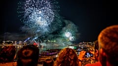 People look at fireworks over the Danube river and the parliament during celebrations to mark Hungary's national day in Budapest on August 20, 2021.