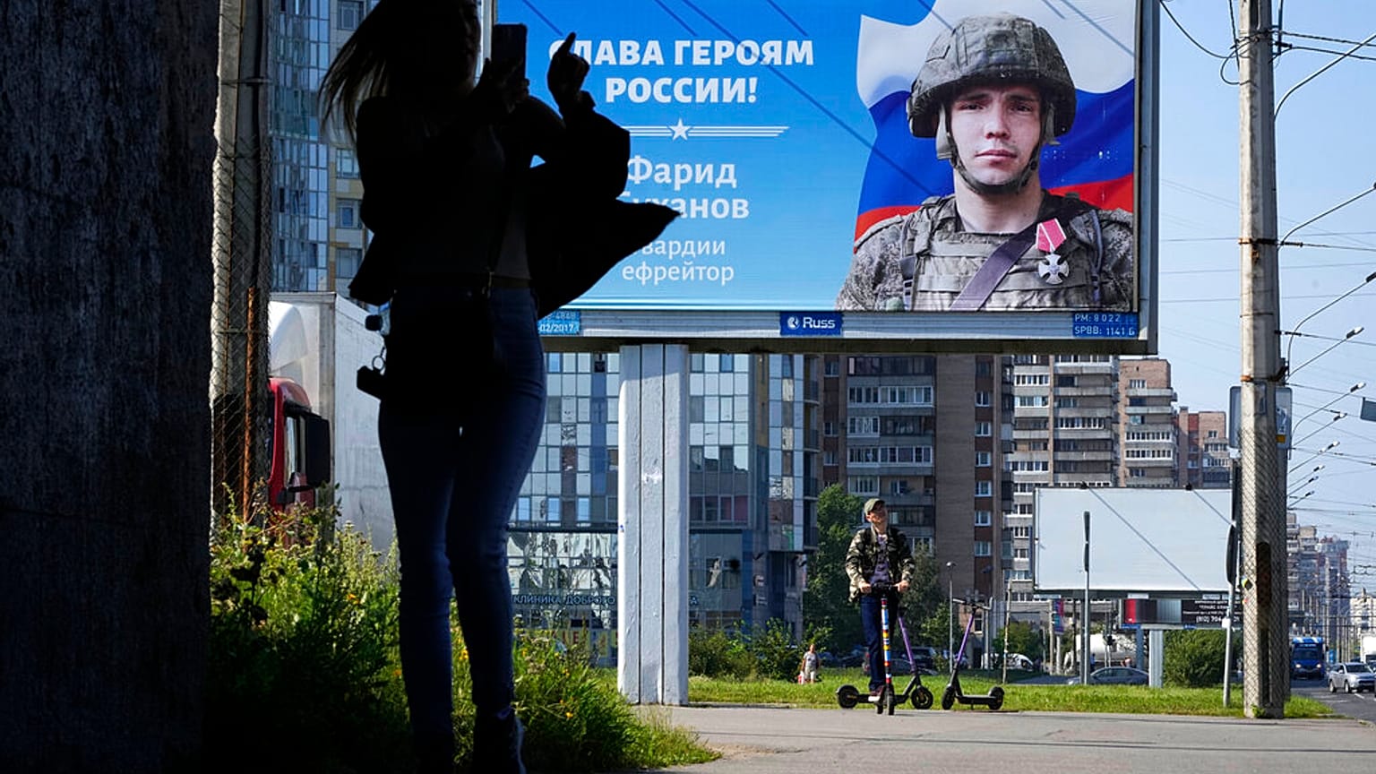Une femme photographie un panneau publicitaire affichant le portrait d'un soldat et l'inscription "Gloire aux héros de Russie" à Saint-Pétersbourg, Russie le 20 août 2022.
